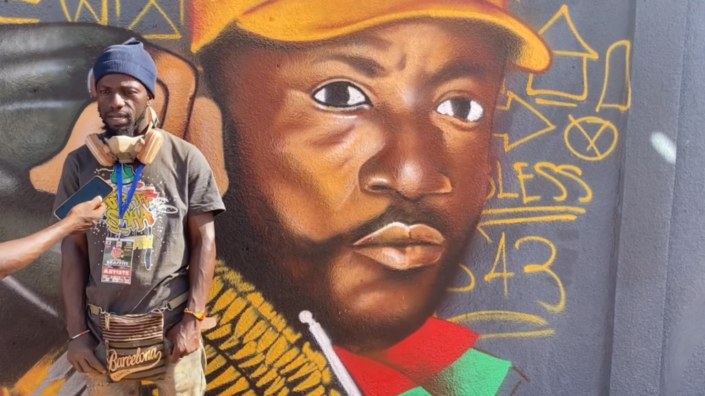 Ousmane Guigma alias Manoos, Artiste-graffeur burkinabè et coordonnateur du festival, avec en filigrane feu "Ladji Yoro"