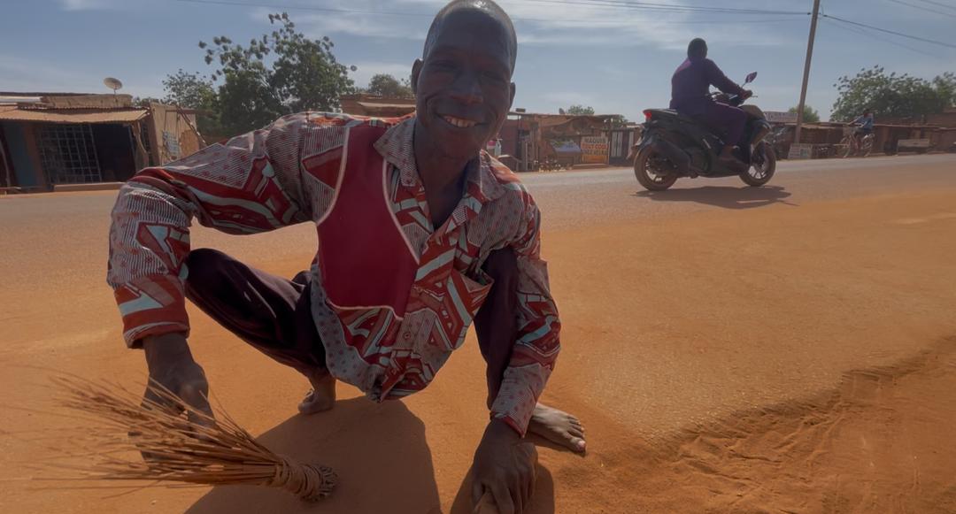 Bila Compaoré, handicapé moteur, balayait les abords de la route