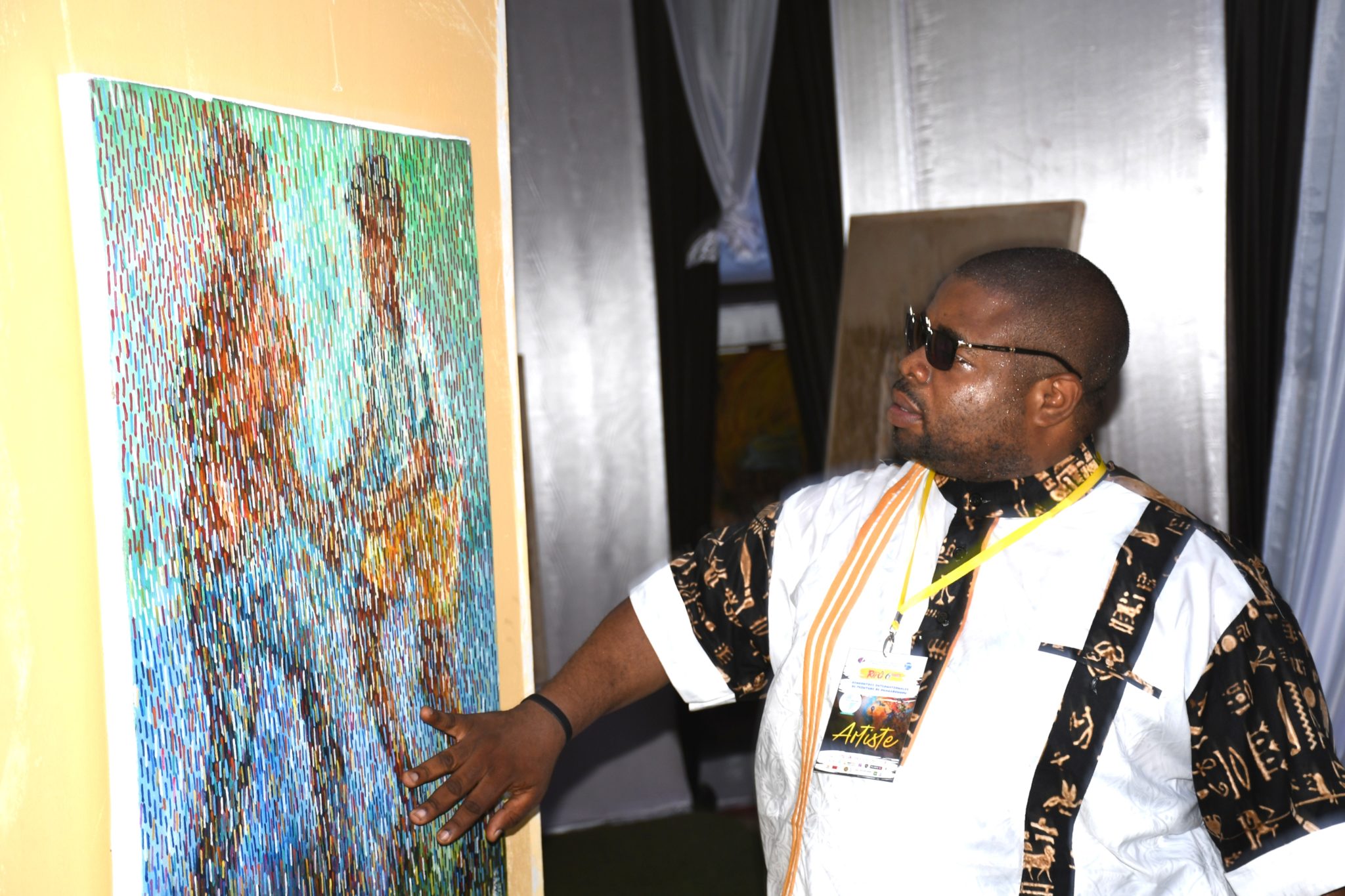 Baba Tshikama devant ses tableaux phares célébrant le vingtième anniversaire des RIPO